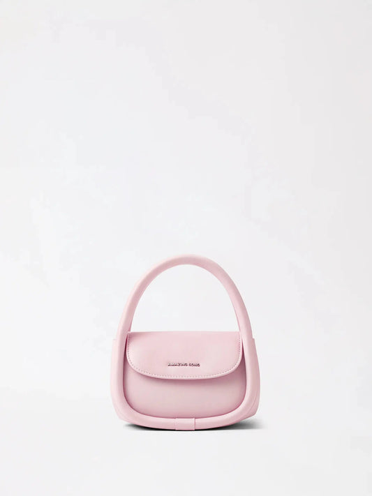 A rounded bakery-inspired leather shoulder bag in warm tan on a linen surface