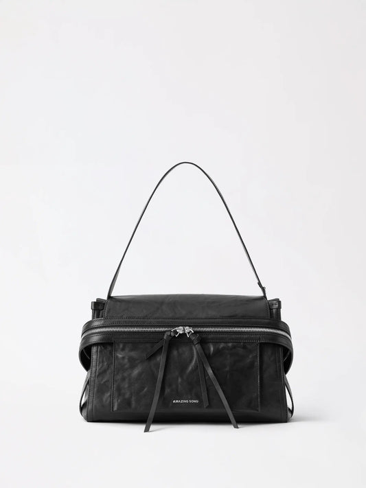 Cheese roll briefcase in tan top-grain leather standing upright on a desk with a laptop beside it