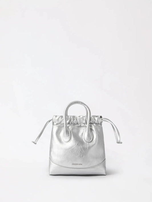 A relaxed slouchy leather hobo bag with an adjustable chain strap resting on a chair