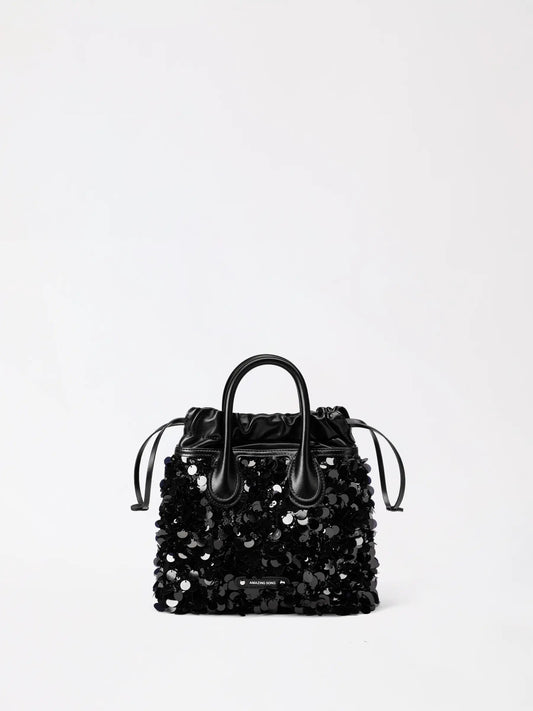 A black sequin leather hobo bag catching warm evening light