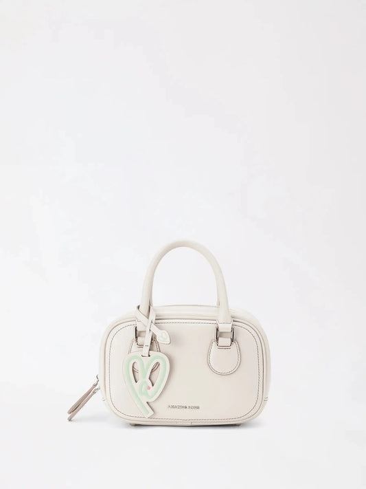 A small toast-slice shaped crossbody bag in warm tan worn against a tonal beige knit