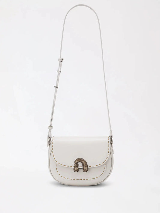 Chestnut-brown structured top-handle bag with a smooth matte finish, sitting upright on a dinner table
