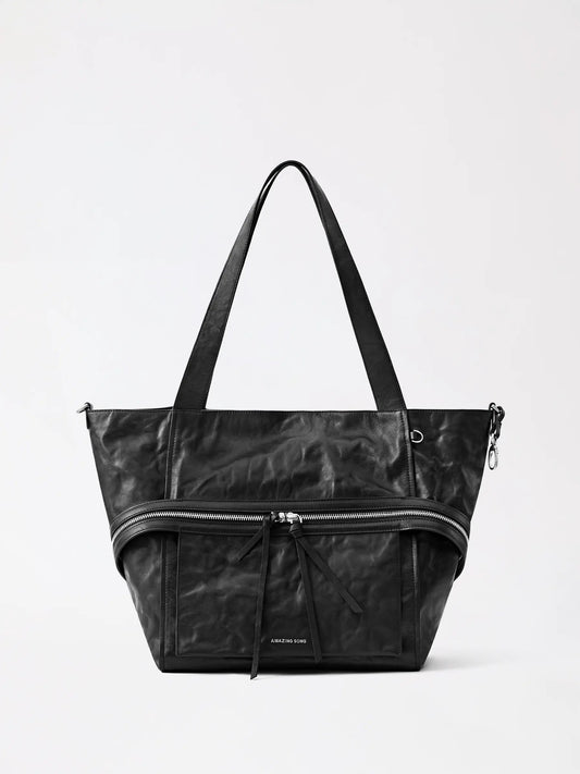 A soft tan cheese-roll leather tote bag resting on a wooden table