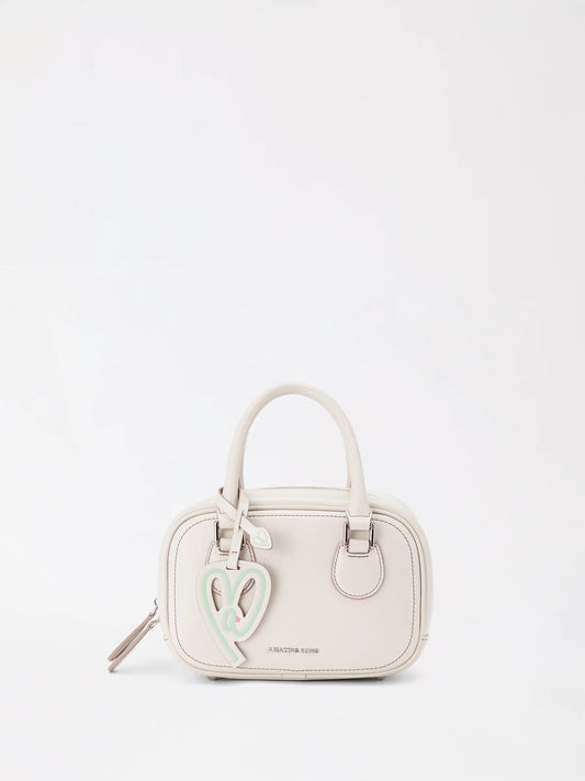 A small toast-shaped leather mini bag in warm tan worn crossbody over a cream knit