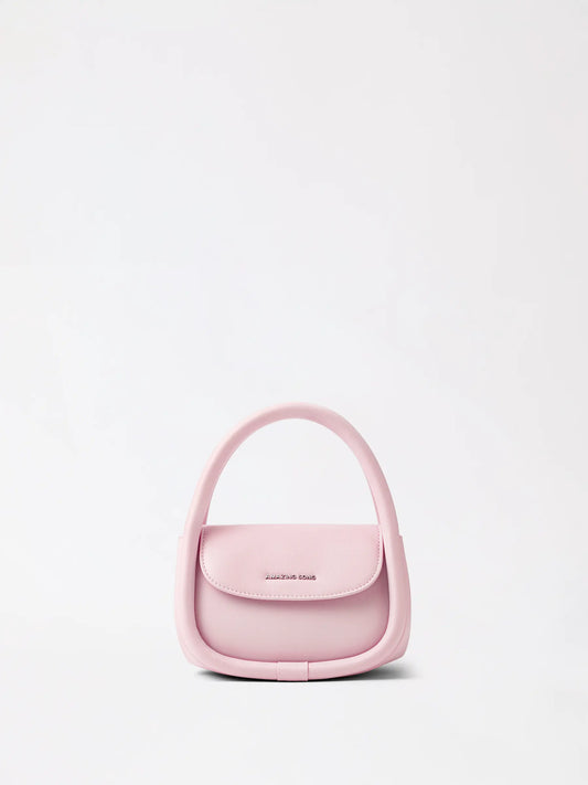 A medium soft oval leather bag in warm tan resting against a neutral knit, shown as the everyday anchor piece