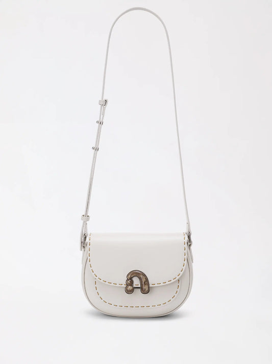 Chestnut brown top-grain leather small bag resting on a wooden table with soft daylight