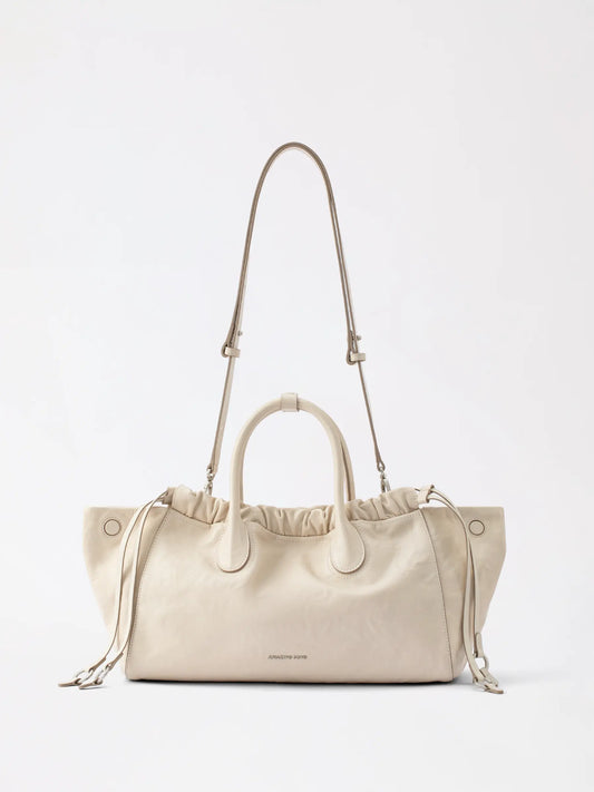 Woman holding a soft rounded cloud-hobo leather bag on a cream coquette date outfit