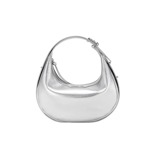 A small half moon leather bag in warm tan resting on a soft knit