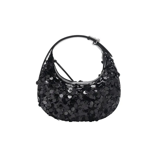 A small sequin half-moon leather bag styled for evening on a warm neutral surface