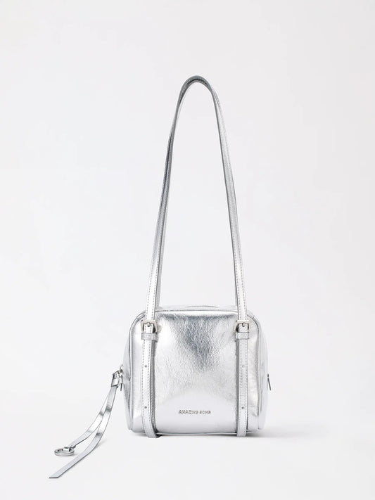 A structured square cowhide handbag standing upright on a wooden table