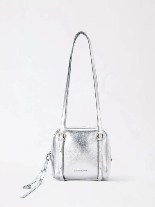 A structured square cowhide handbag standing upright on a wooden table