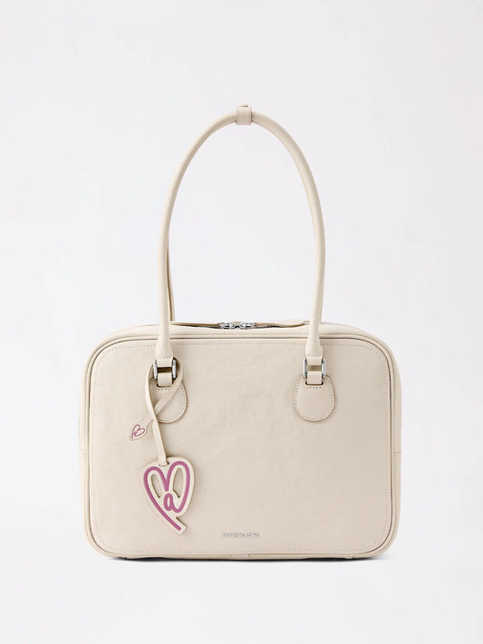 A large toast-shaped top-grain cowhide leather bag in warm tan resting on a linen table