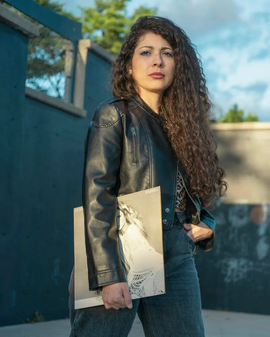 a woman in a black leather jacket holding shopping bags