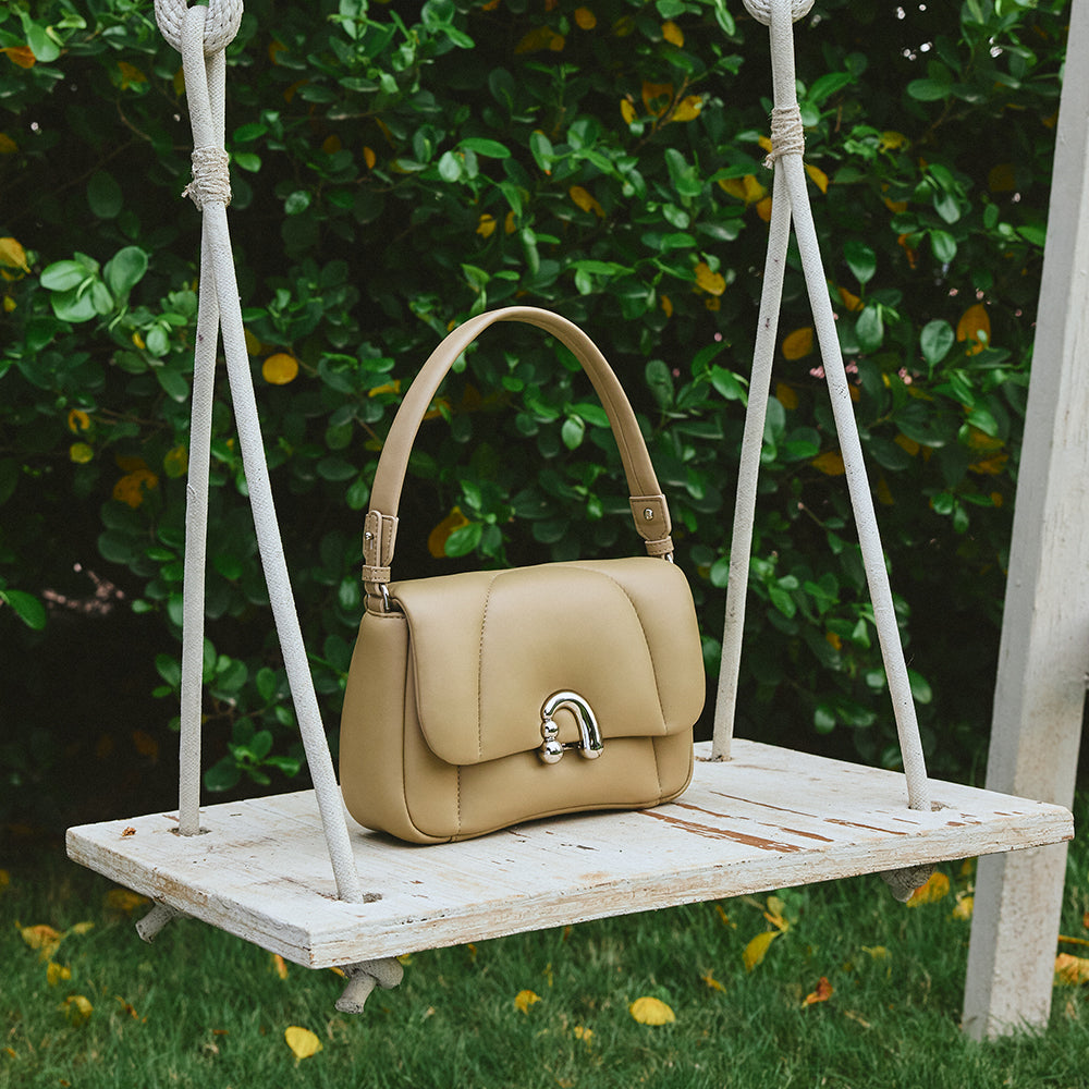 Beige leather handbag on wooden swing, Amazing Song official product, garden background