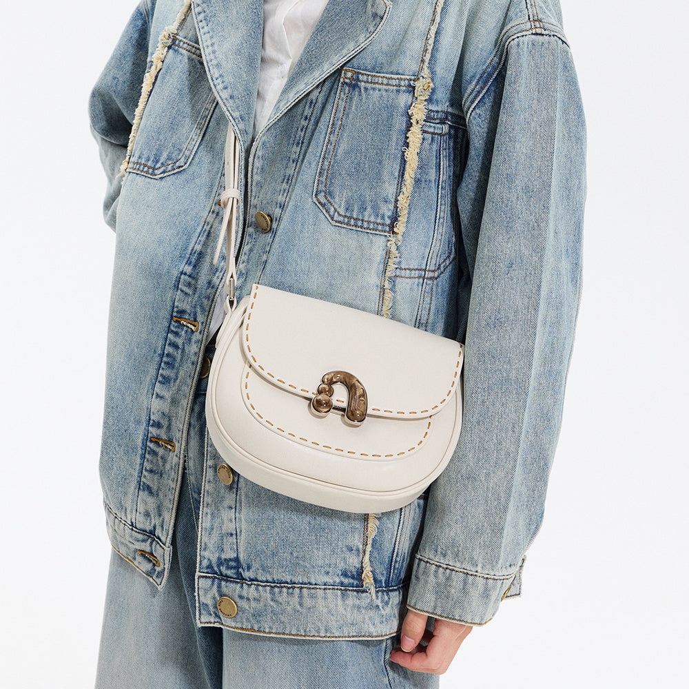 White crossbody handbag with gold clasp on denim jacket, Amazing Song fashion accessory