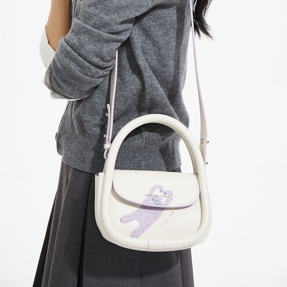 Woman wearing gray sweater and skirt, carrying Amazing Song white shoulder bag with purple bear design