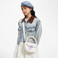 Woman in blue beret, denim jacket, and white skirt with a cute bear print shoulder bag