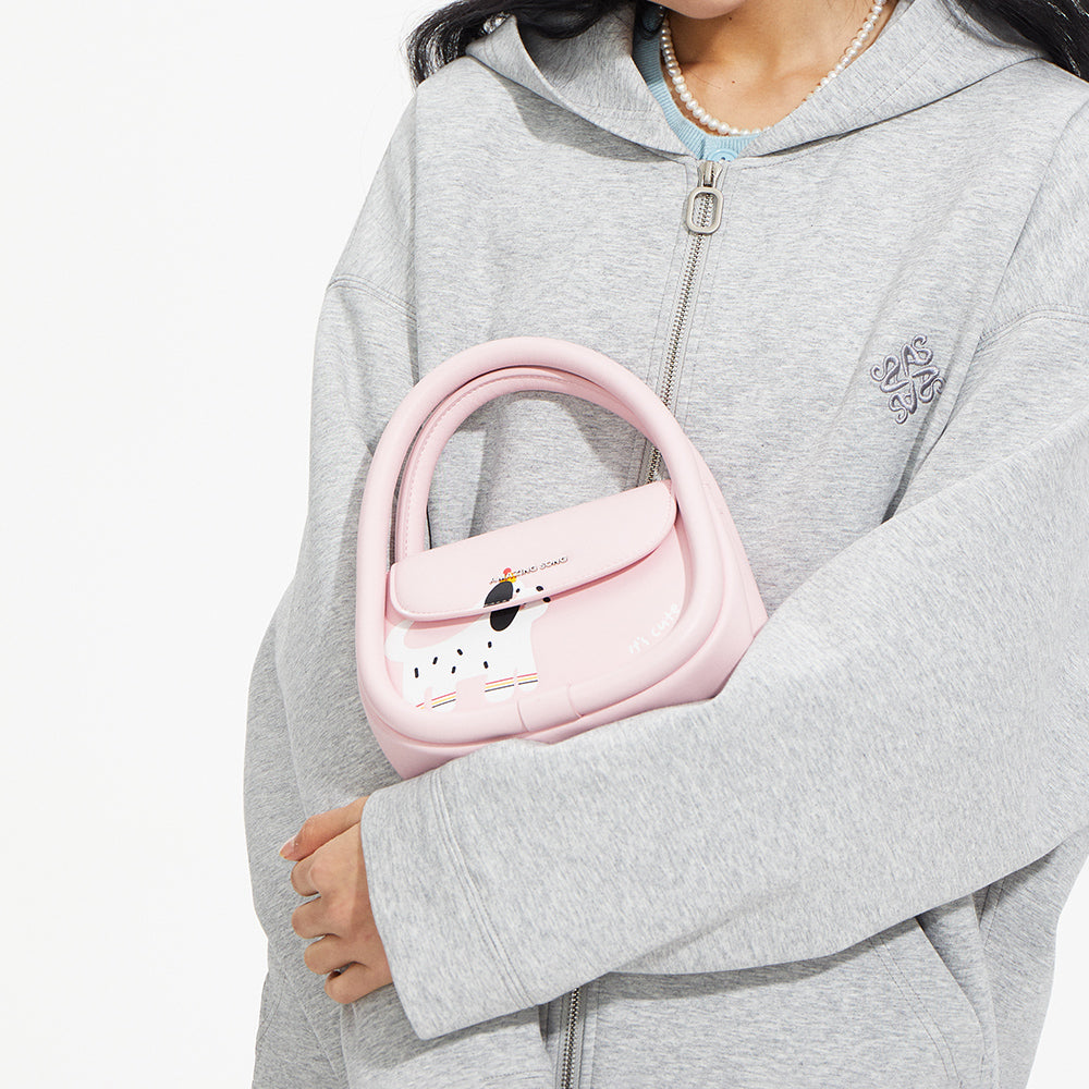 Woman in grey hoodie holding pink Amazing Song handbag with dog print