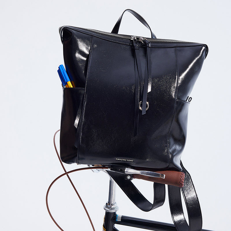 Amazing Song black leather backpack on bicycle seat with pens in pocket