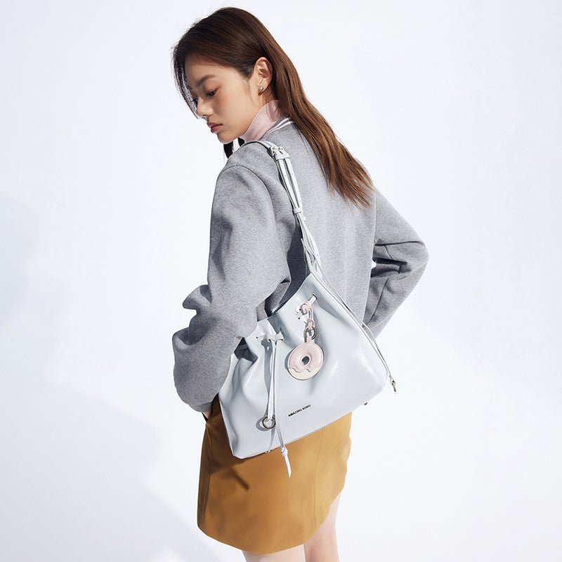 Woman wearing grey blazer and tan skirt with Amazing Song light blue handbag