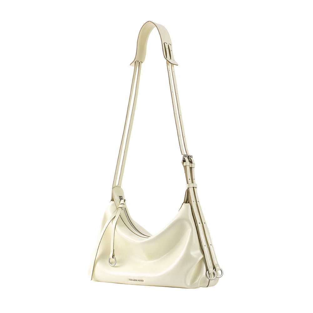 Cream leather shoulder bag with adjustable strap and silver hardware on white background