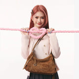 Woman with pink hair holding a pink rope, wearing a light sweater and brown suede bag from Amazing Song.