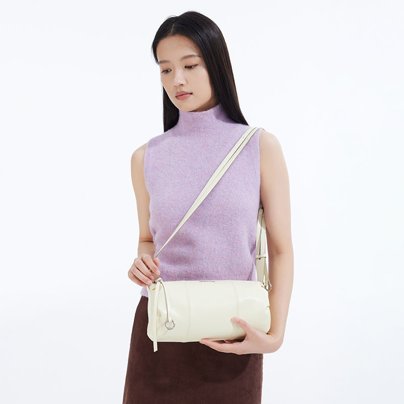 Woman in a lavender sleeveless top holding a cream shoulder bag, Amazing Song style