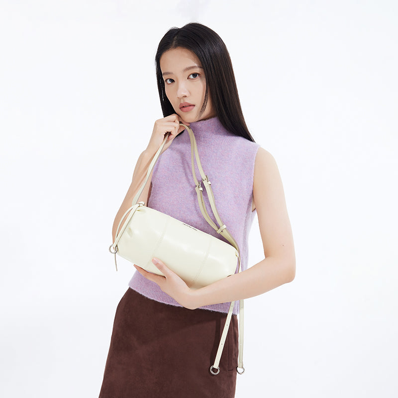 Woman in lilac sleeveless top and brown skirt holding a cream shoulder bag, Amazing Song