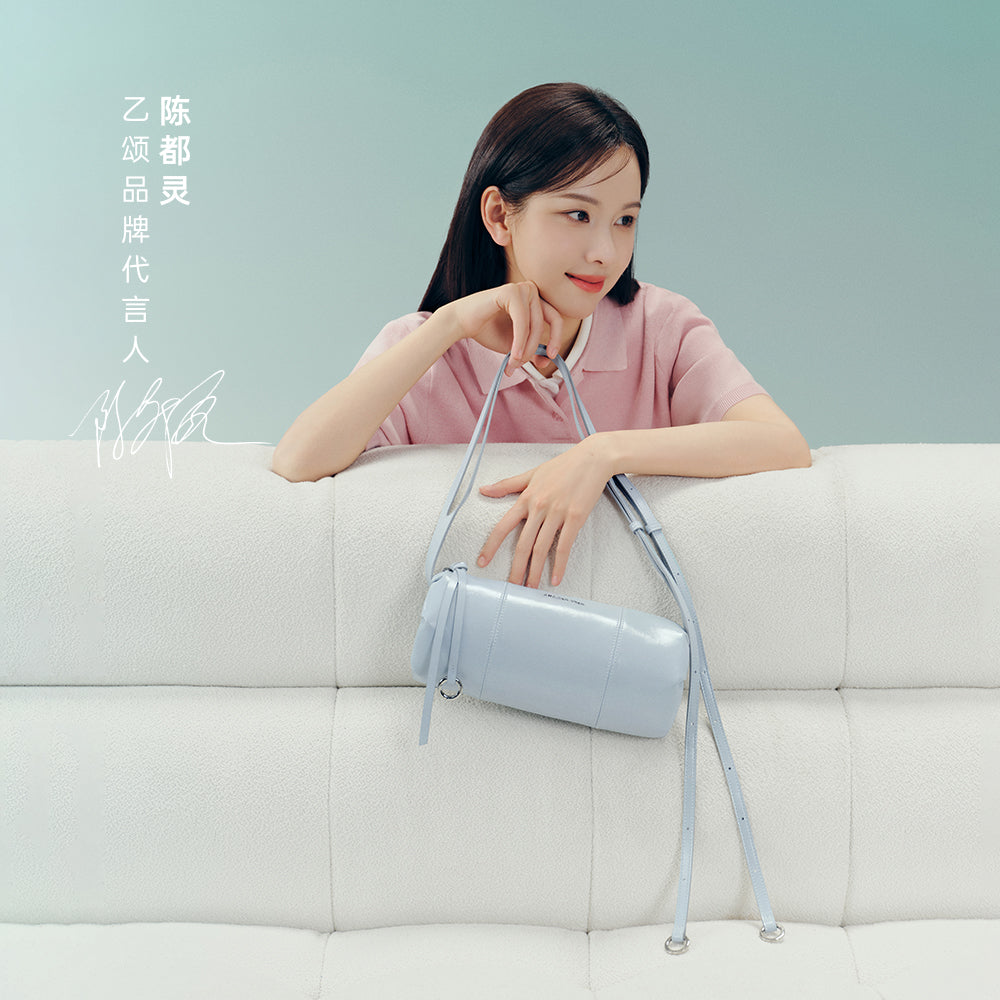 Woman in pink top on white sofa holding a light blue handbag, Amazing Song official website