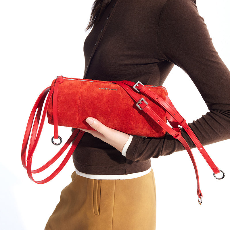 Woman holding vibrant red suede Amazing Song handbag with adjustable straps