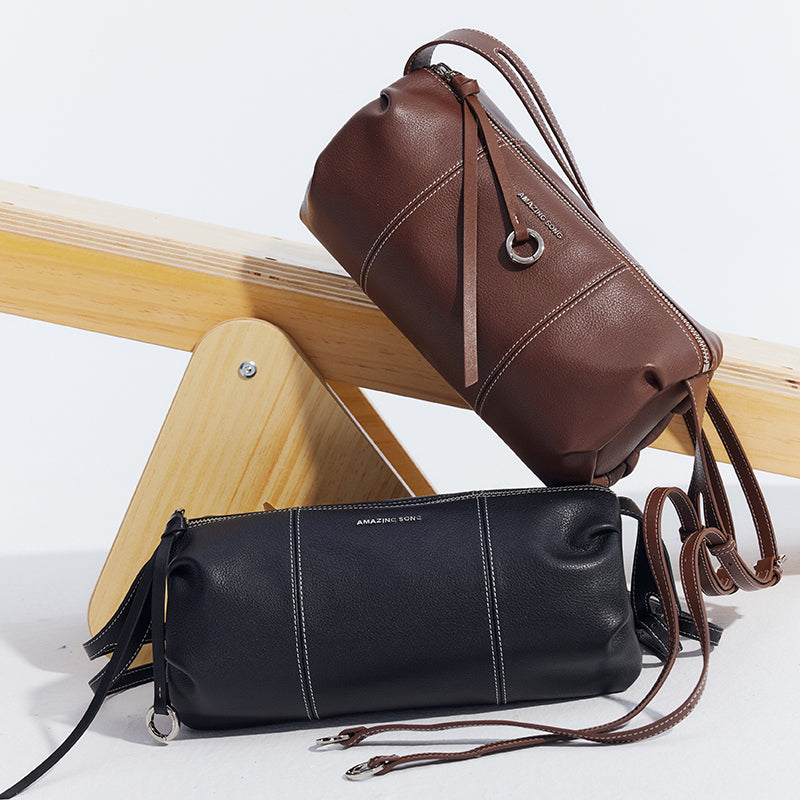 Amazing Song black and brown leather shoulder bags on light wood stand, minimalist style