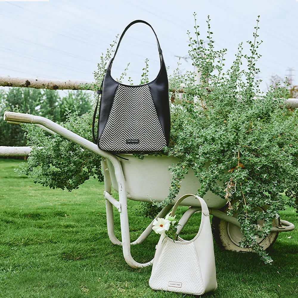 Fashion handbags by Amazing Song displayed on a white wheelbarrow in a garden setting