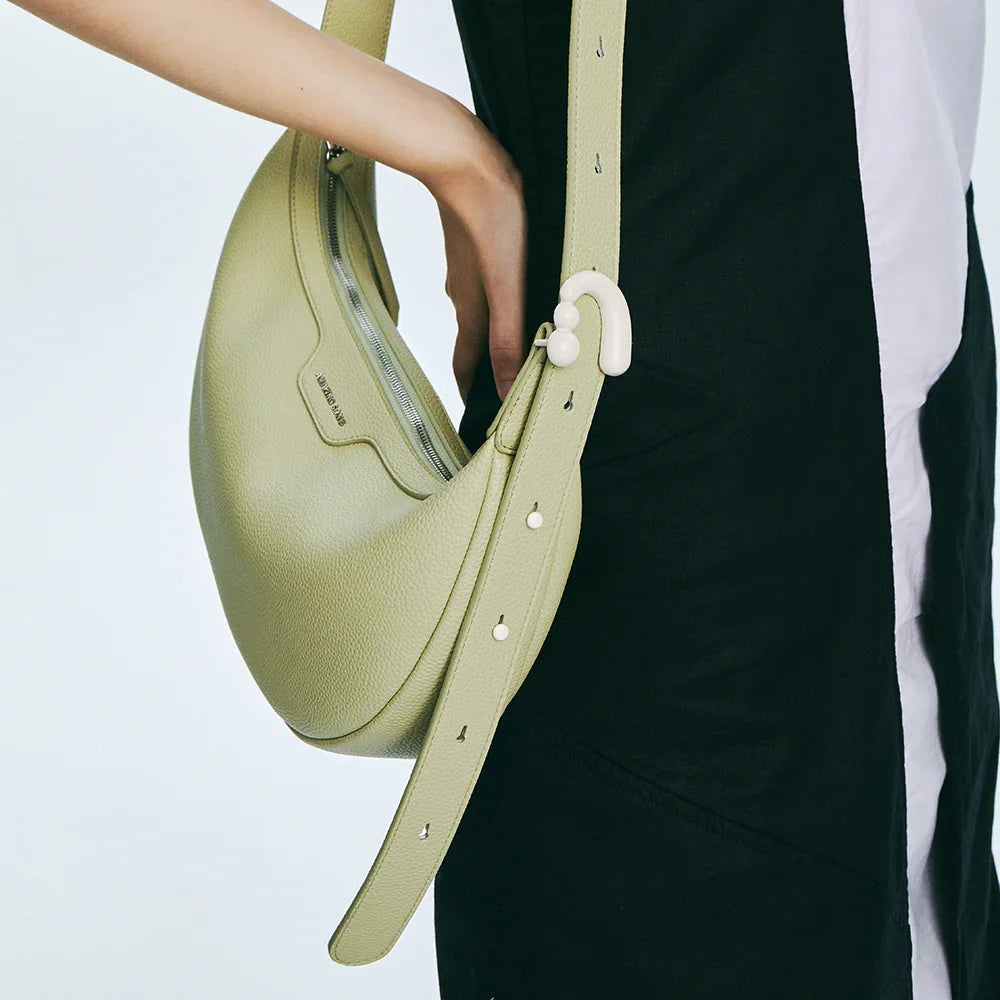 Close-up of green leather Amazing Song shoulder bag with adjustable strap on model