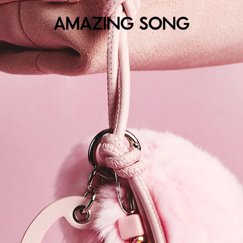 Close-up of pink faux fur handbag with leather strap, Amazing Song branding, pastel background