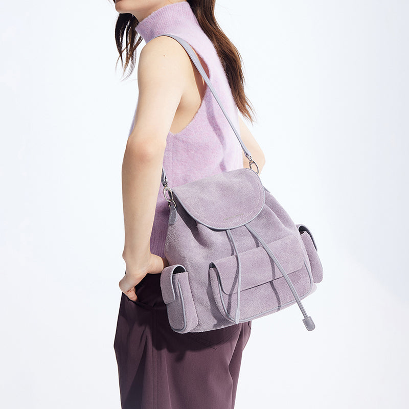 Woman in sleeveless lilac top modeling a light purple suede backpack, Amazing Song official site