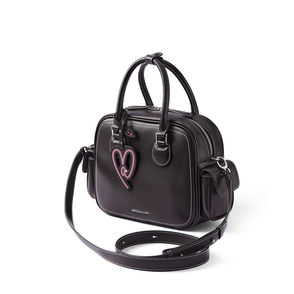 Black Amazing Song handbag with pink heart charm, double handles, and white stitching
