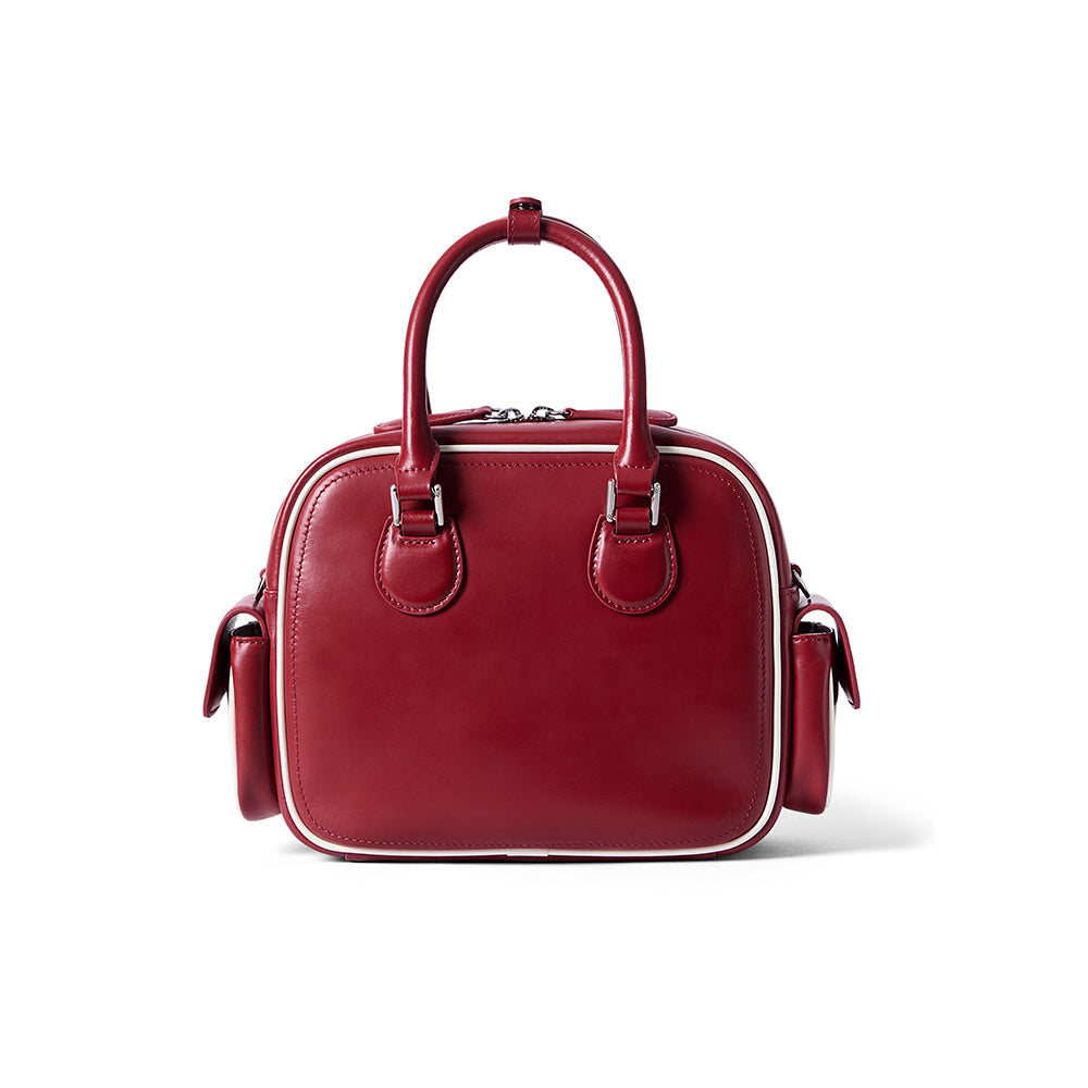 Red leather handbag with double top handles and side pockets on white background