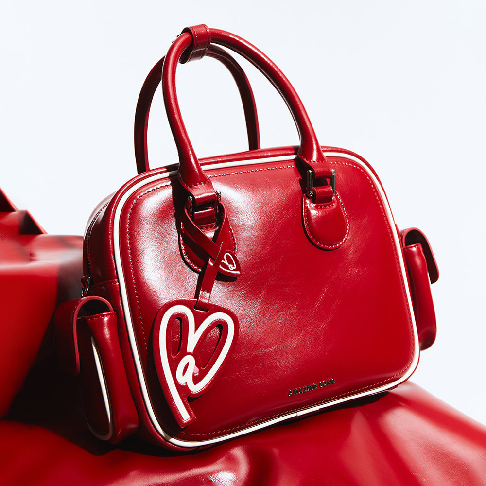 Amazing Song red leather handbag with white trim and heart tag on white background