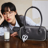 Woman with glasses beside a black Amazing Song handbag and glass of milk on table