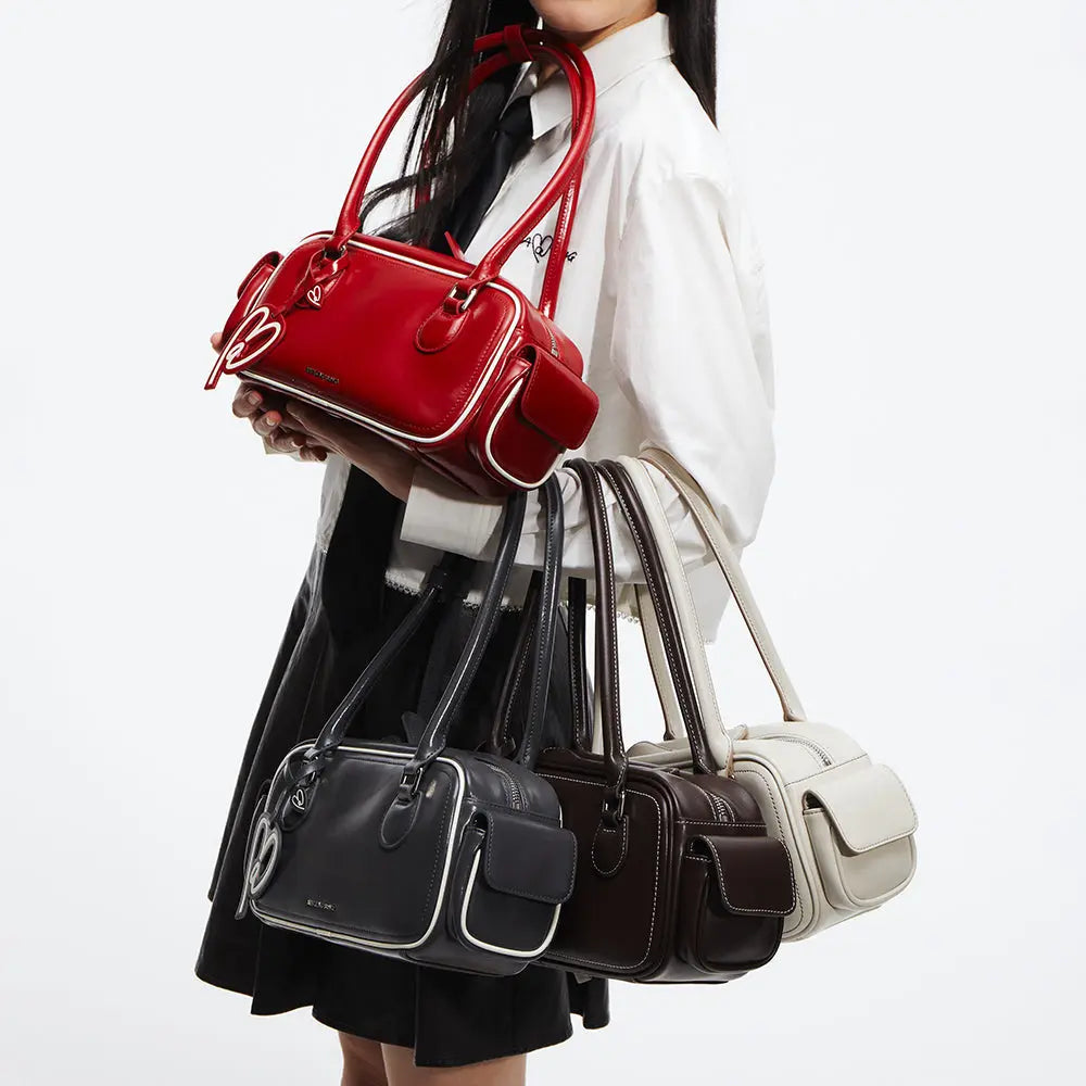 Woman holding Amazing Song handbags in red, black, brown, and cream on white background