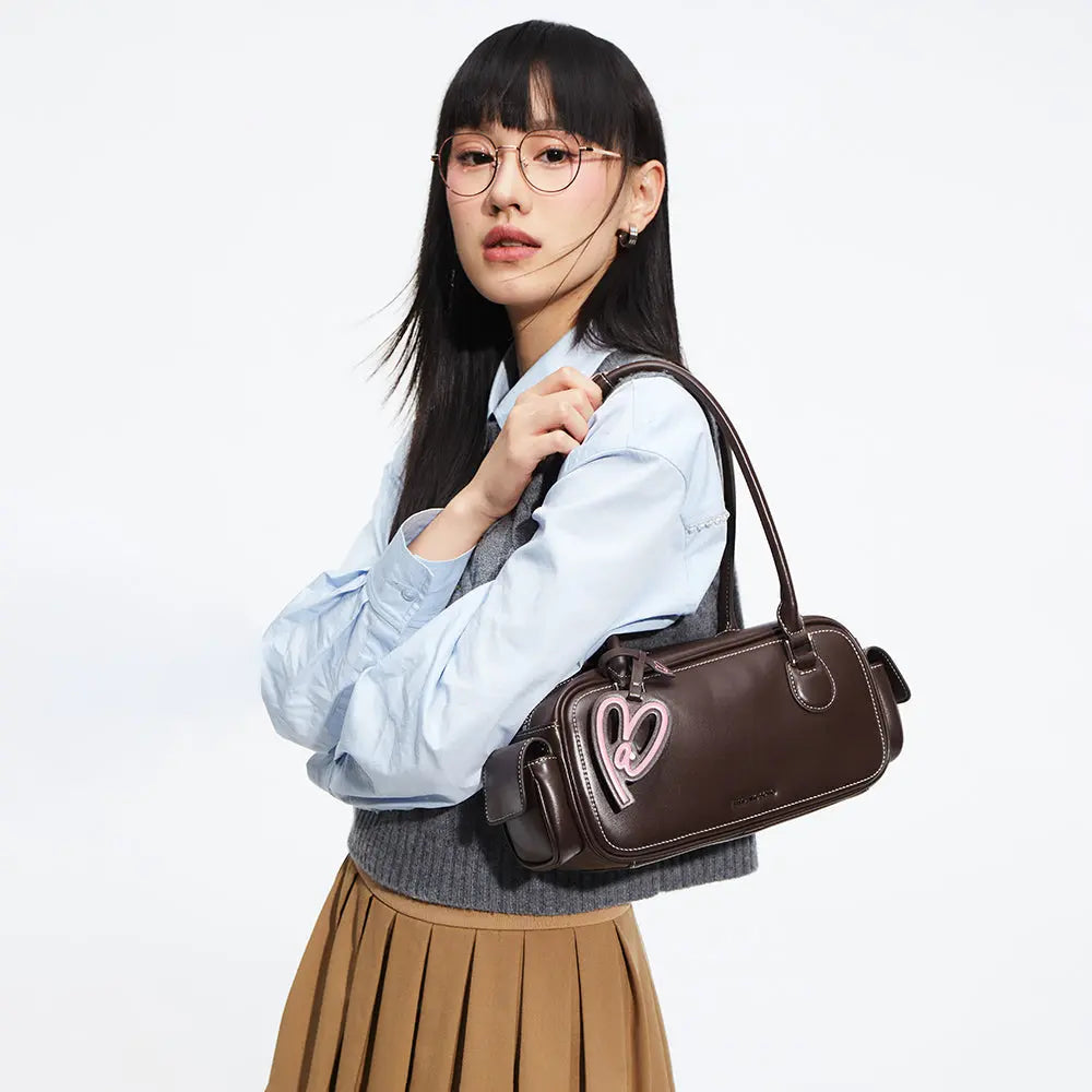 Woman wearing glasses with a brown shoulder bag featuring pink heart detail from Amazing Song