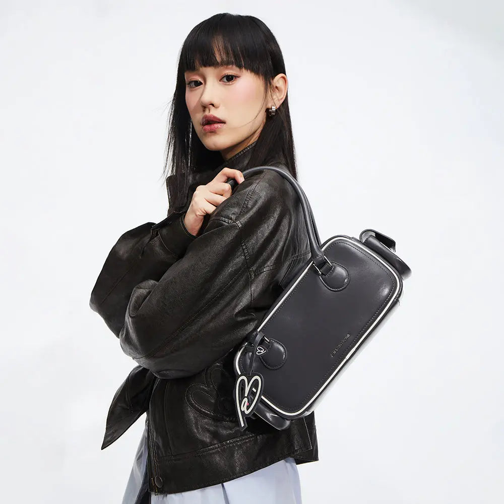 Woman in black leather jacket carrying a stylish black Amazing Song handbag