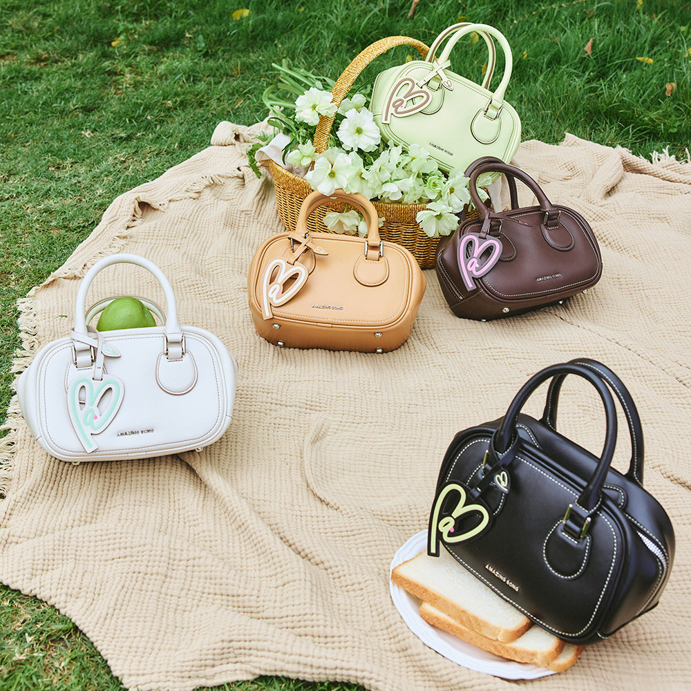 Colorful Amazing Song handbags on picnic blanket with flowers and food outdoors