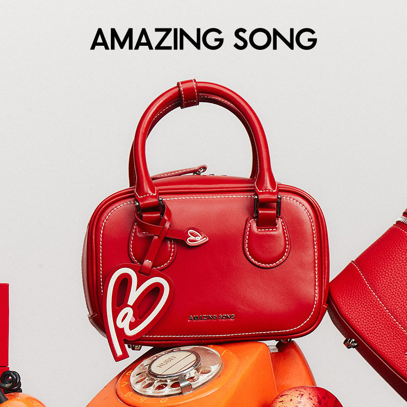 Amazing Song red handbag with heart tag on orange rotary phone, official brand image