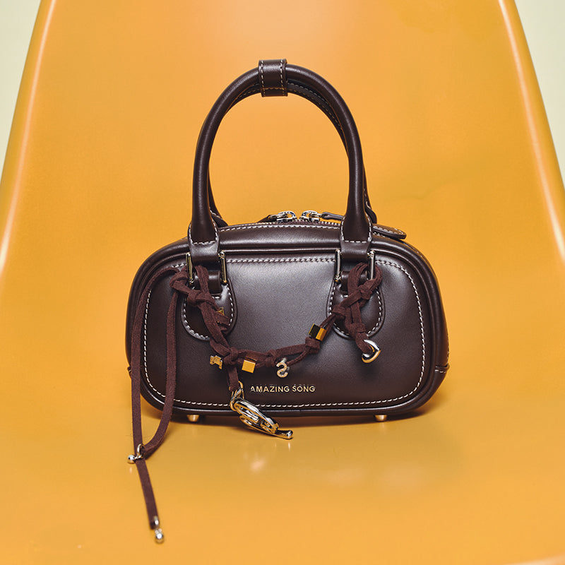 Amazing Song brown leather handbag with braided strap on yellow chair