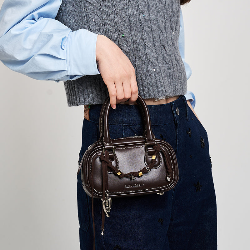 Woman holding brown leather mini handbag, stylish outfit, Amazing Song fashion accessory